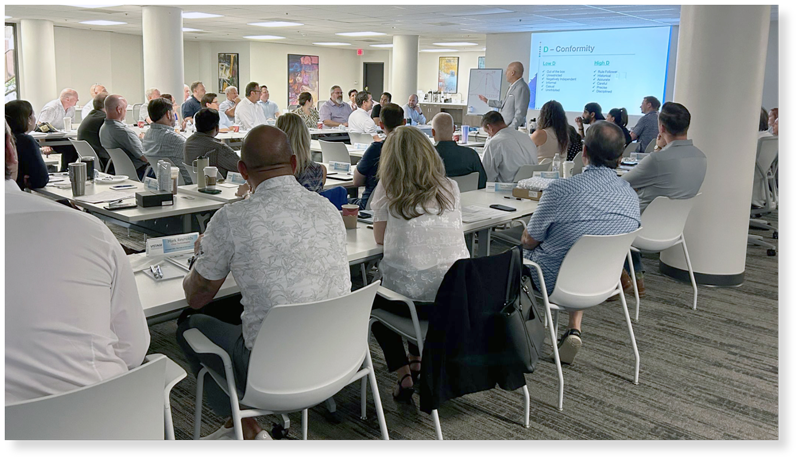 Dennis speaking in front of large group of CEOs in large meeting room